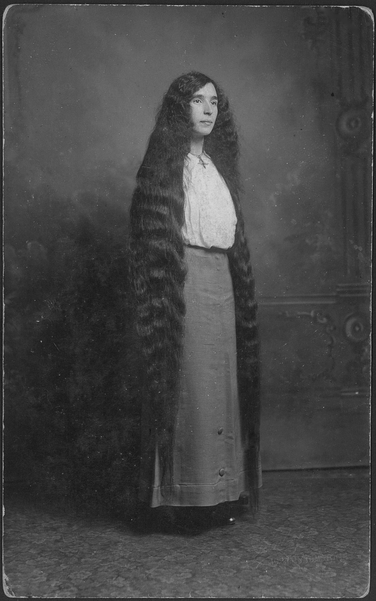 Portrait of a young woman with long hair almost to the floor, circa 1900s